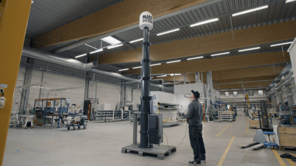 Mastsystem technician operating a fully extended SkyHigh telescopic mast during functional testing at the Mastsystem factory in Heinävaara, Finland.